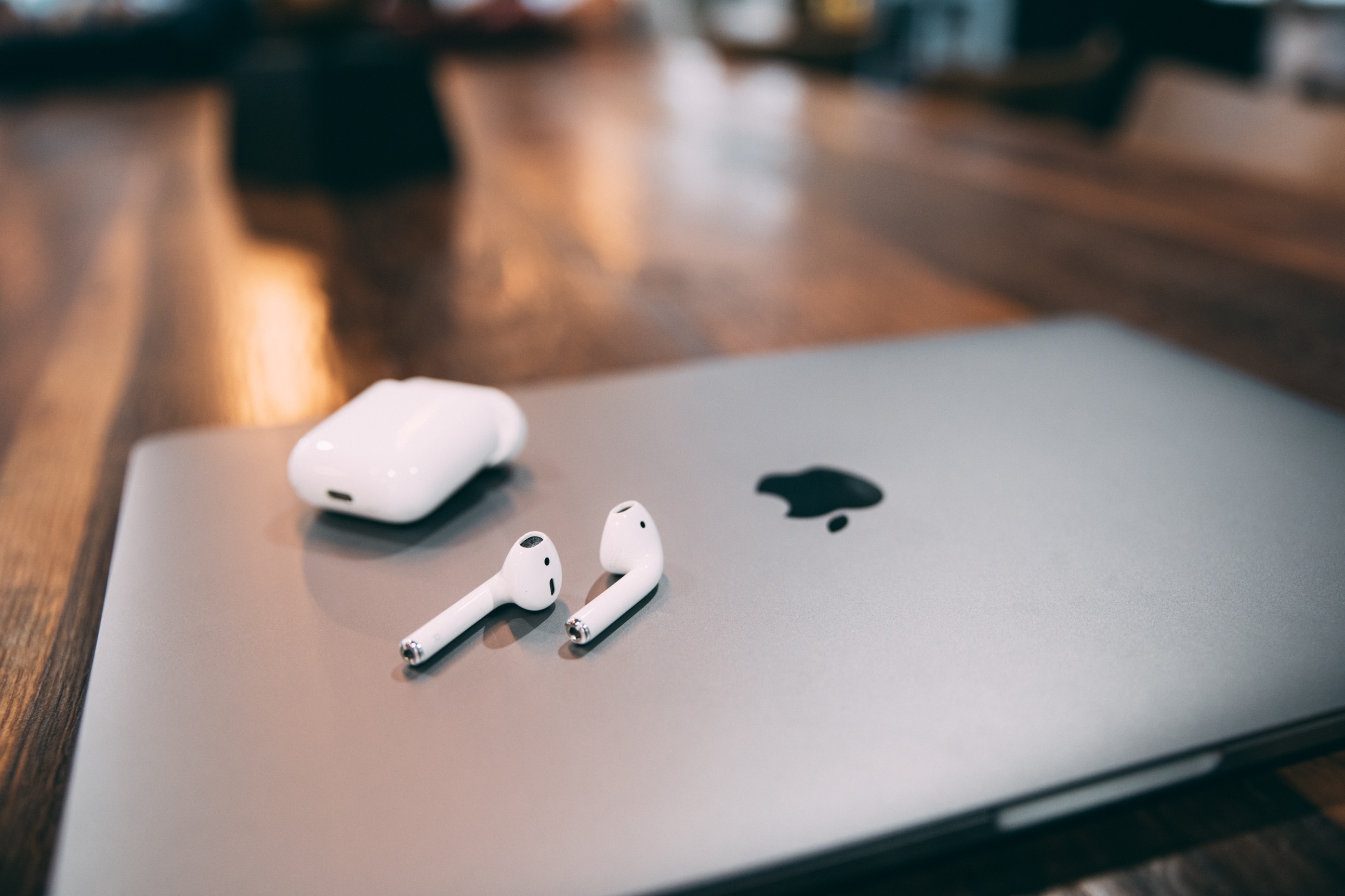 Apple AirPods shown resting on top of an Apple laptop