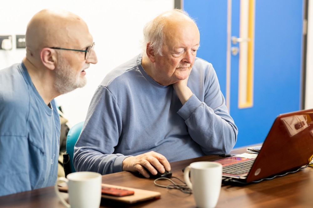 Two older men looking at a laptop