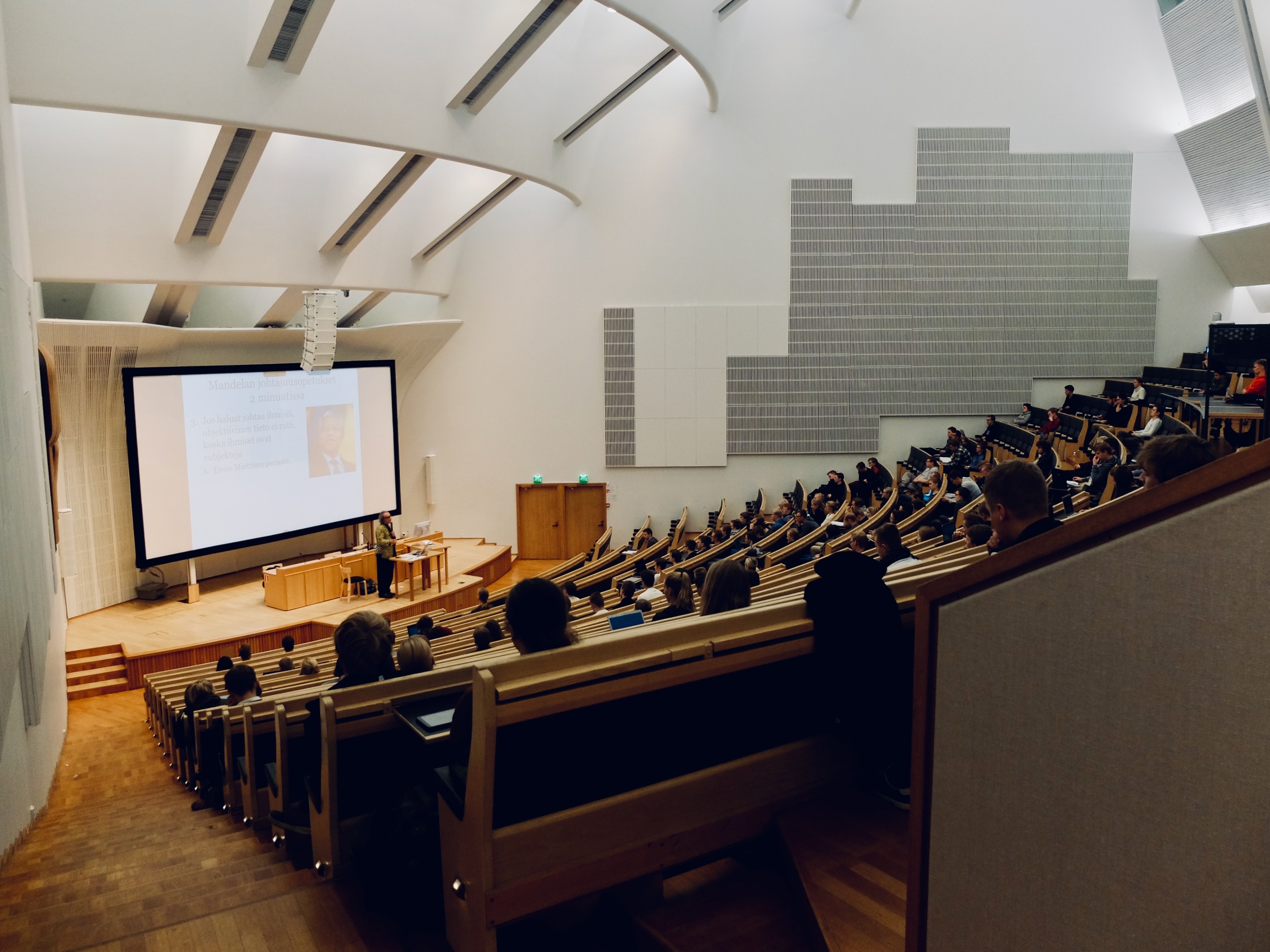 Large modern university lecture hall with teacher presenting in the distance