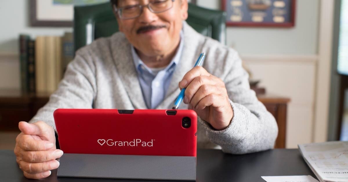 Image shows a man with a moustache looking at a GrandPad device and using it with a stylus-style device