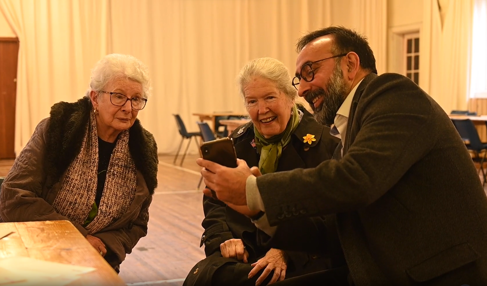 Mohammed Iltaf and older people looking at a device screen and smiling