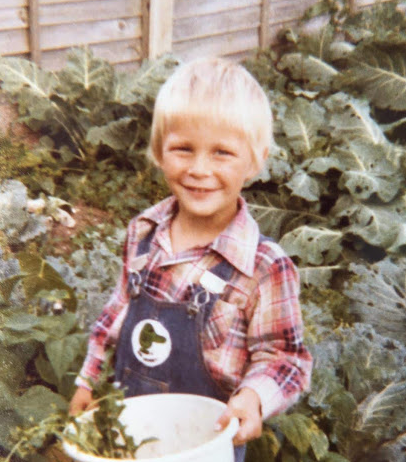 The author as a boy, standing in a vegetable patch holding a bucket 