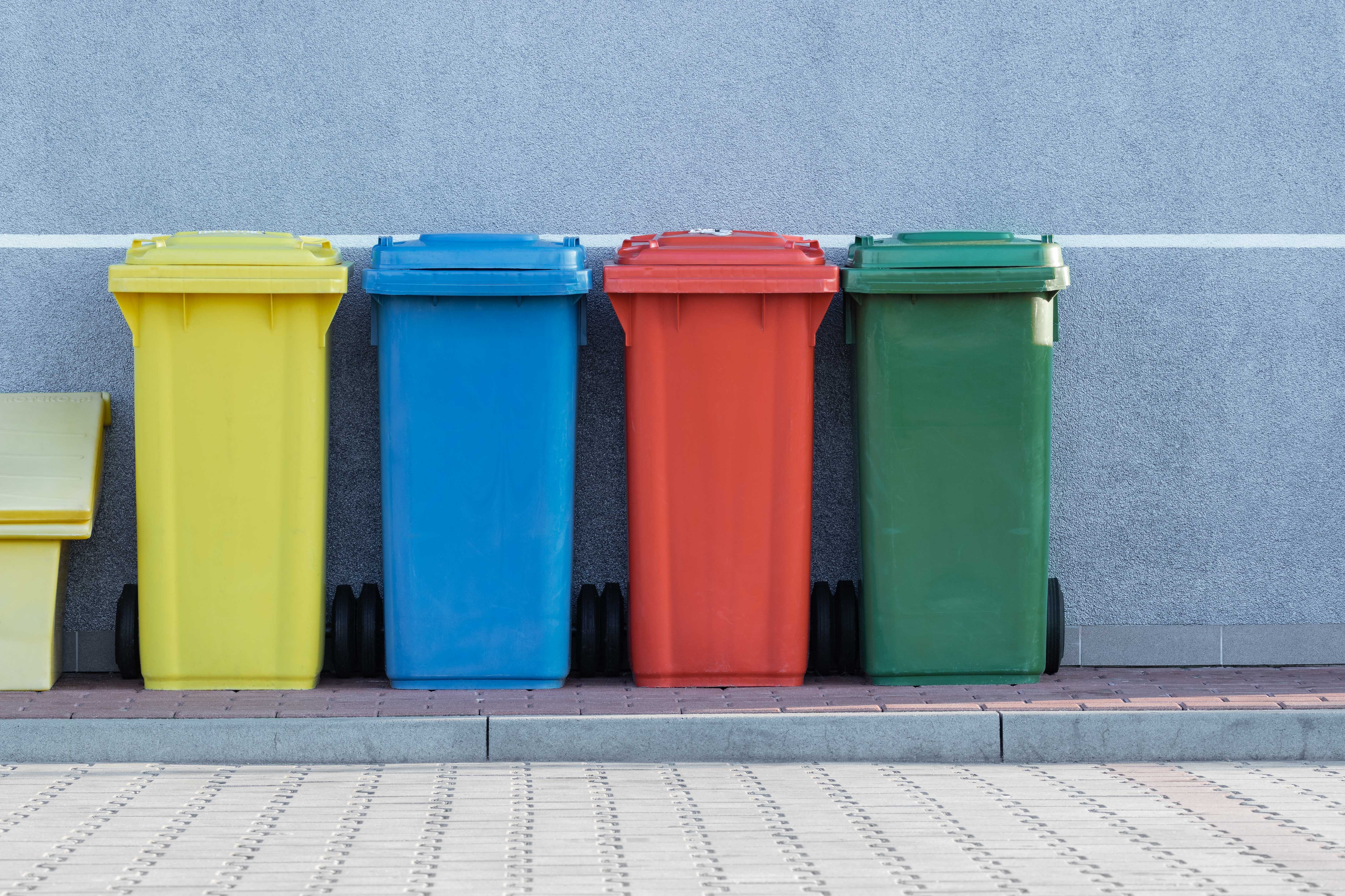 Image shows bins outside they are yellow, red, blue and green