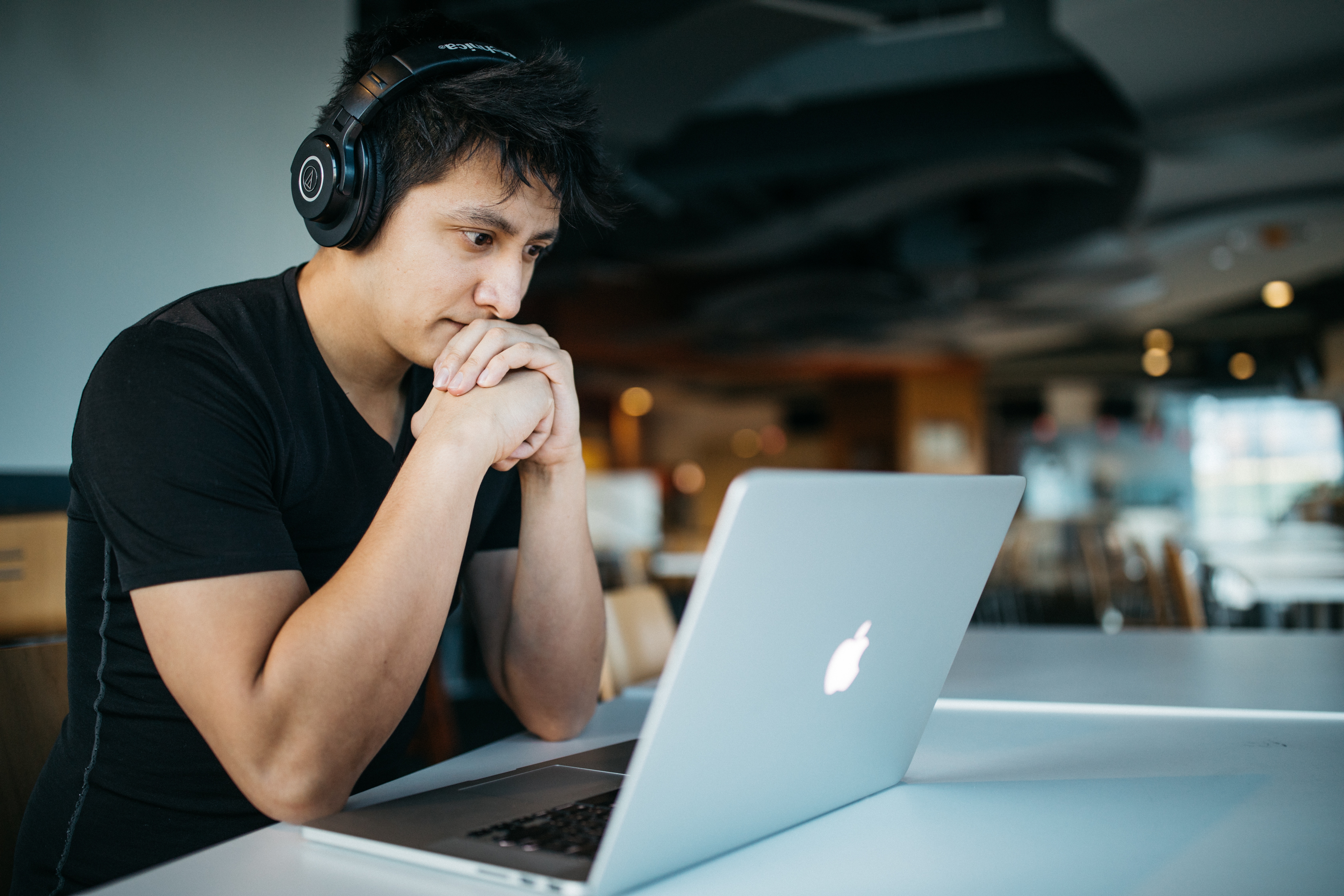 Man studying on his own wearing headphones and watching computer screen