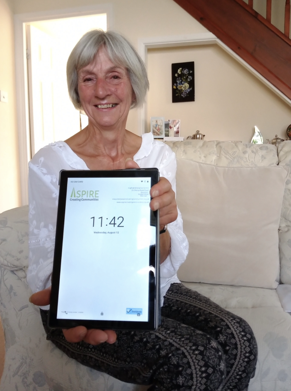 Image shows a recipient of one of the tablets holding it up, and smiling