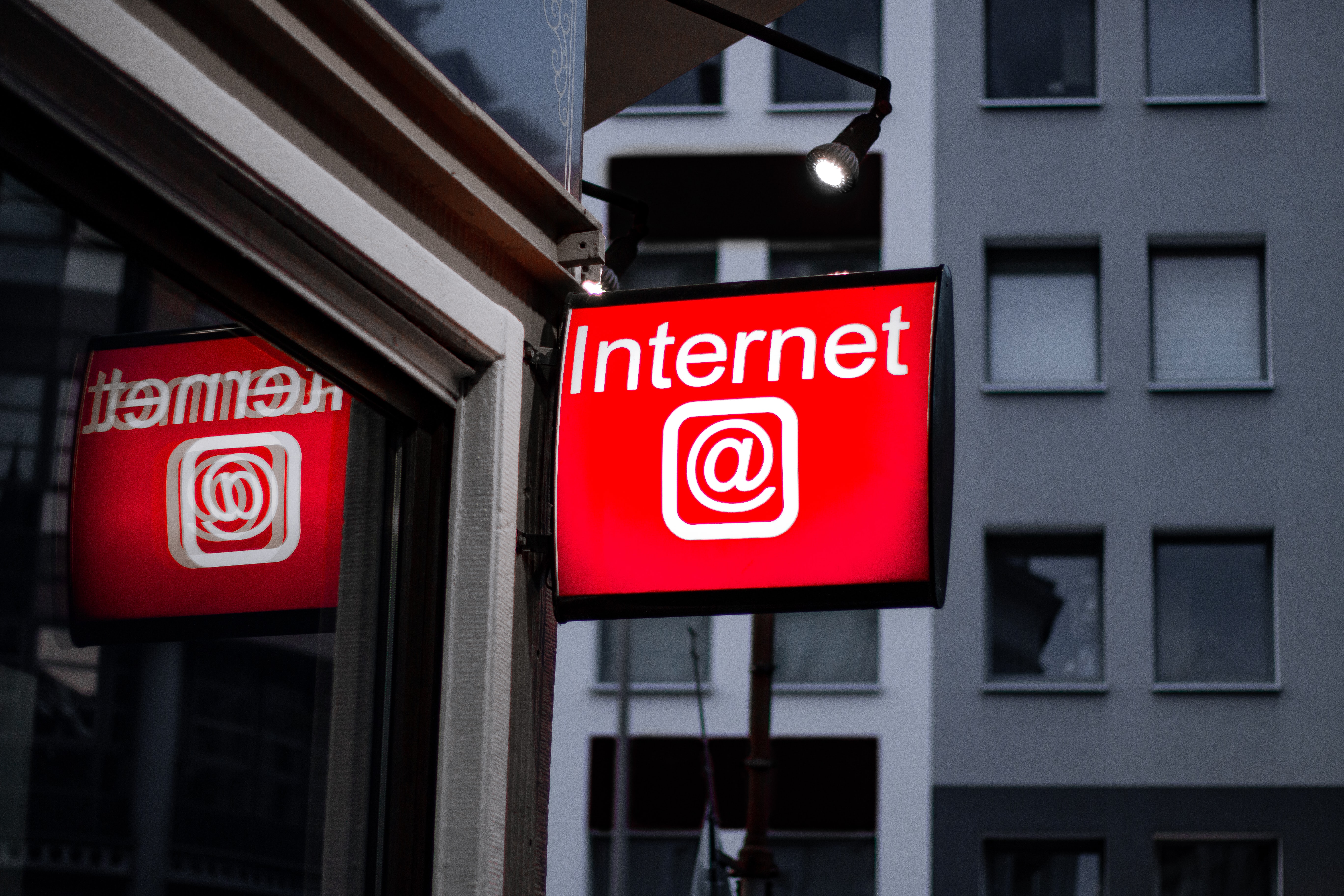 Shows a sign outside a shop that reads Internet with an @ symbol