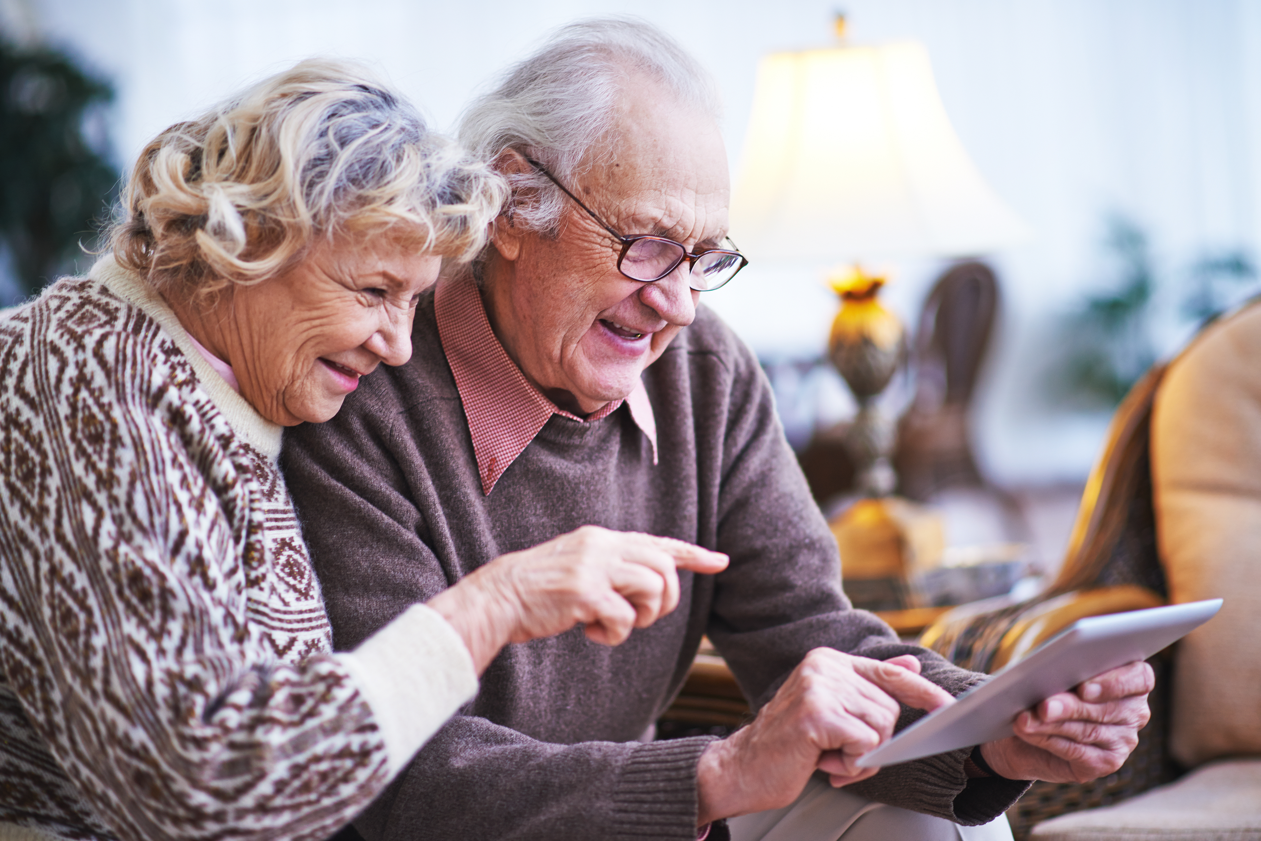 An older couple using a tablet device at home