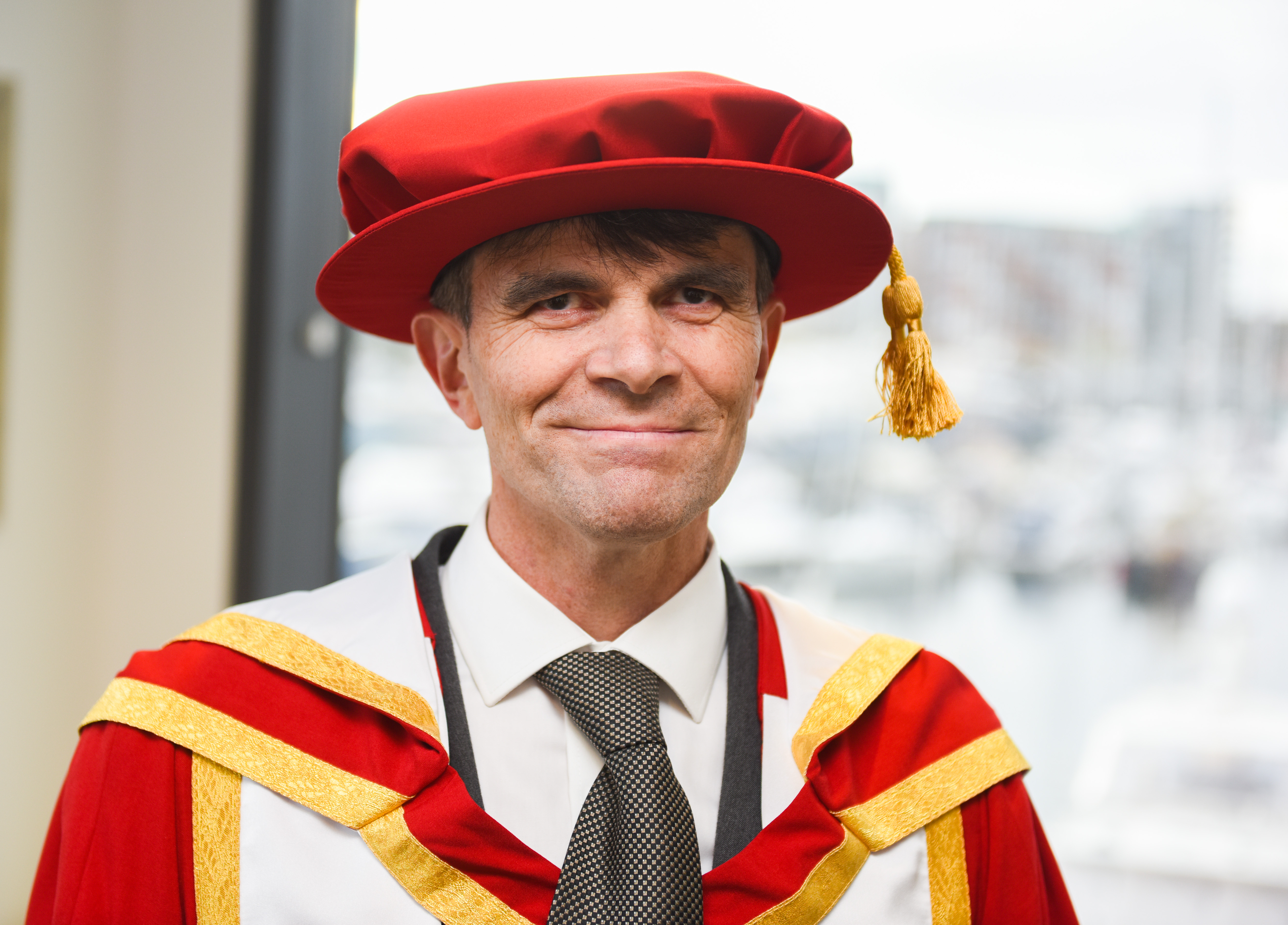 Robin Christopherson standing smiling with graduation robes on
