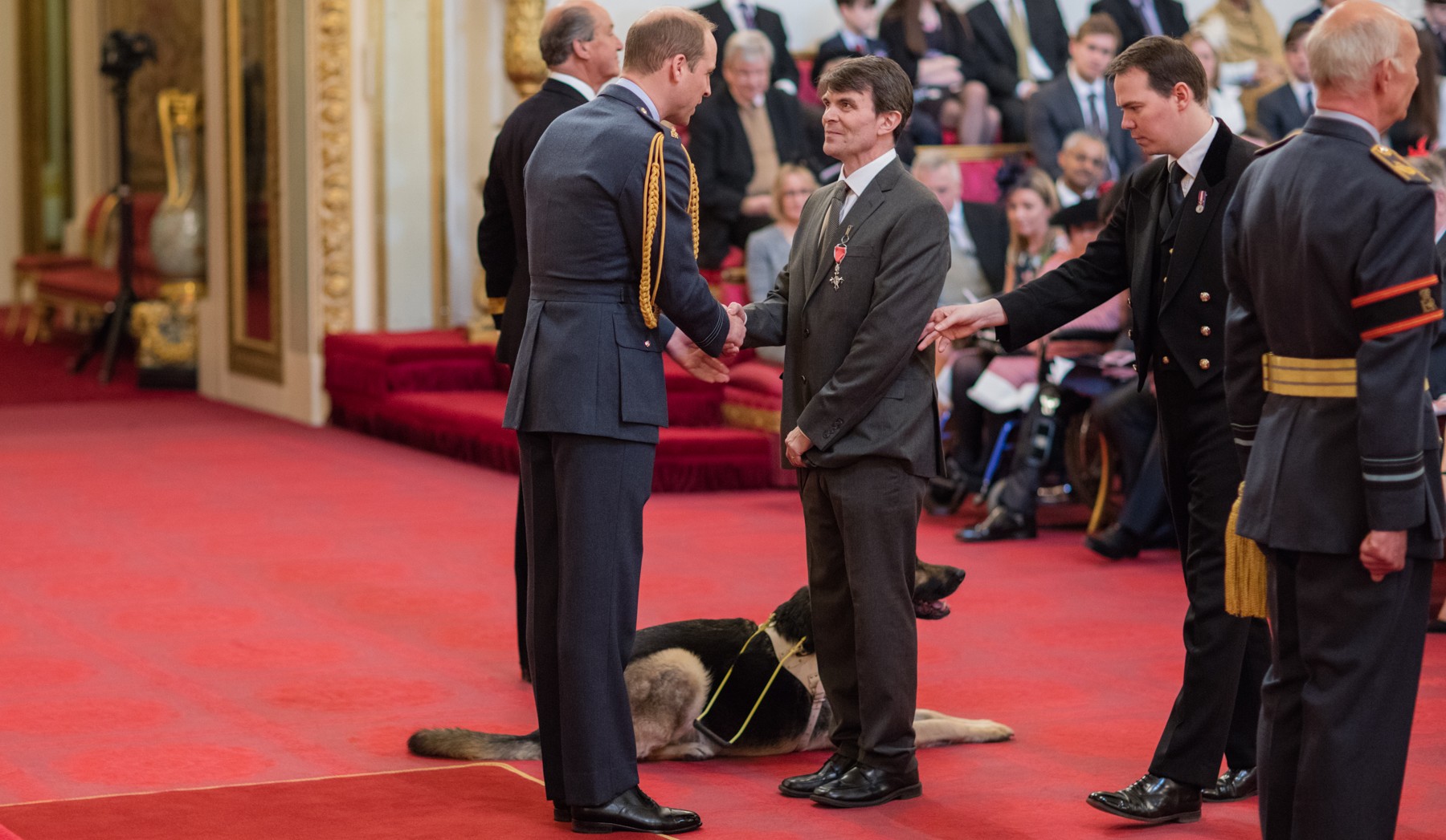 Robin Christopherson receives his MBE from the Duke of Cambridge - all wearing formal clothing standing shaking hands
