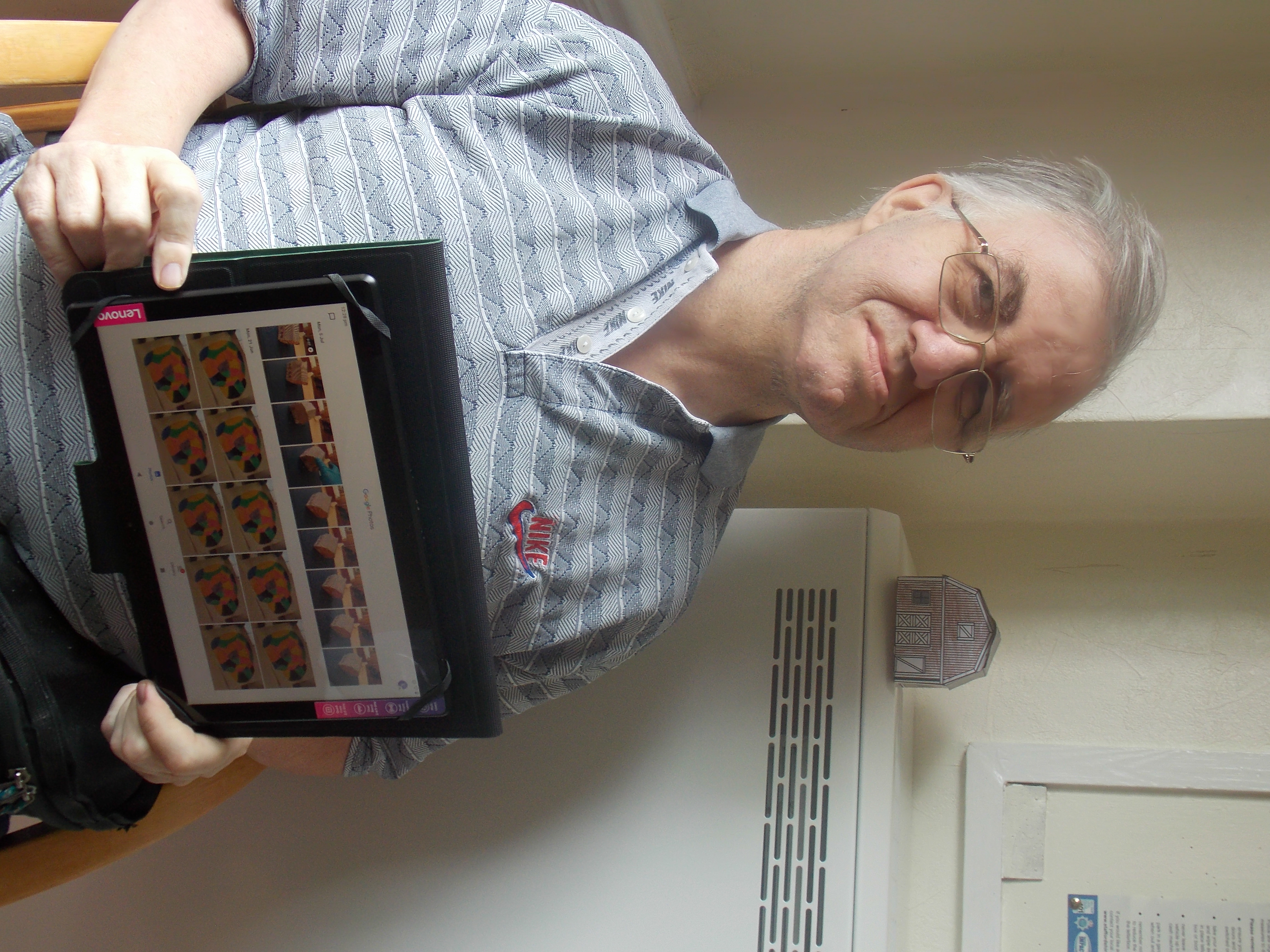 Image shows Stoke-on-trent resident with learning disabilities holding a tablet with pictures of his artwork