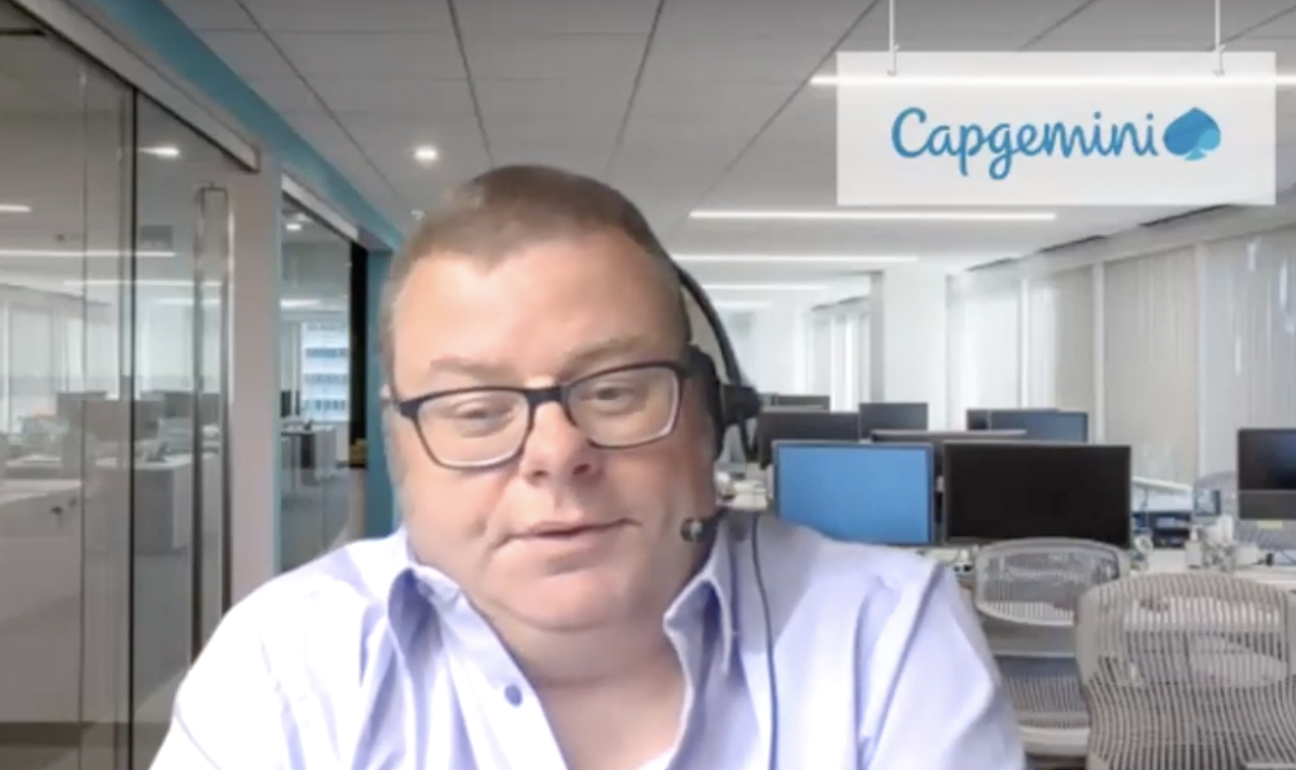 Man sitting in office with the word 'Capgemini' on a board in the background
