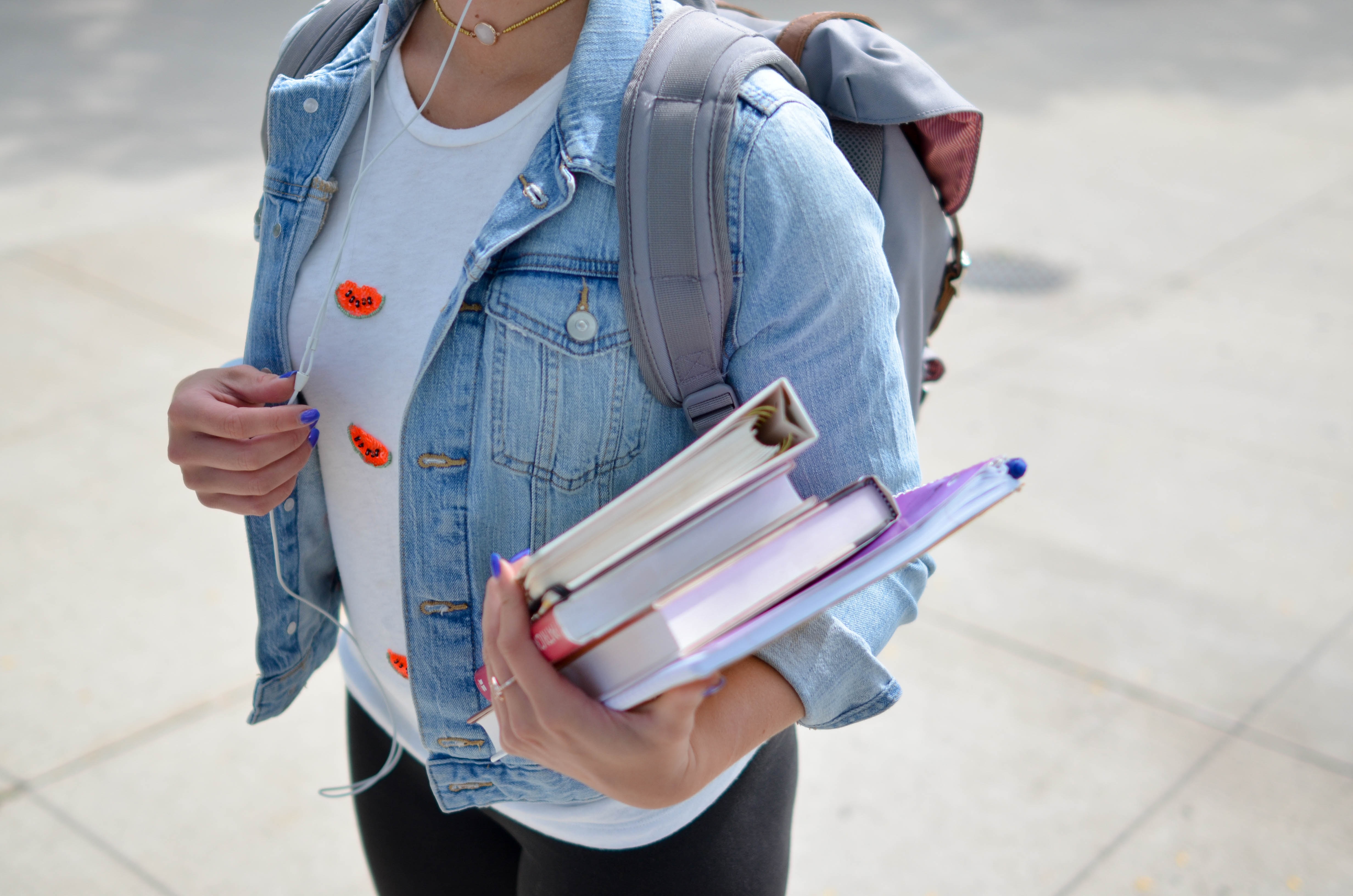 Female student carrying books and backpack wearing headphone