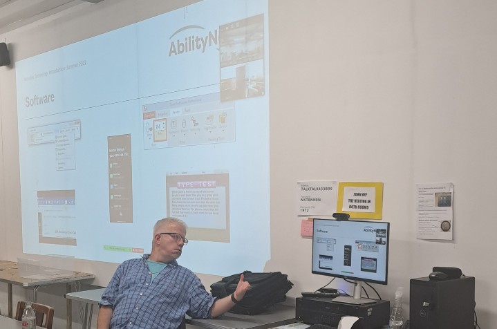 Alex Barker sitting on chair in training room with projector displaying on screen