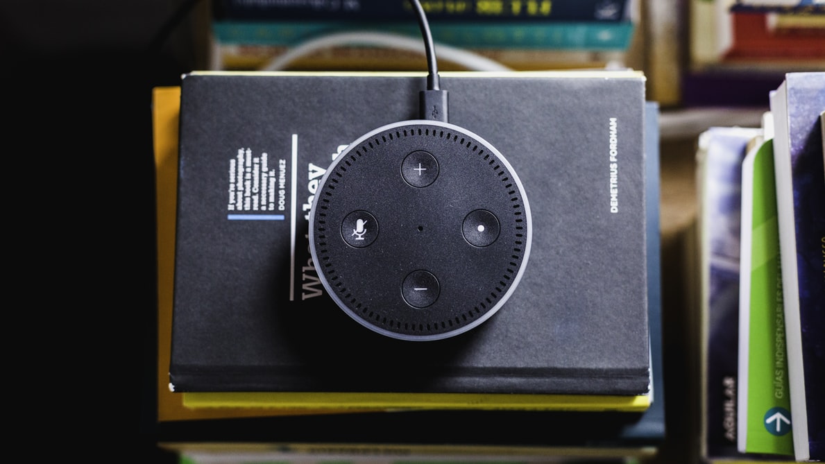 An amazon Echo device on top of a stack of notebooks