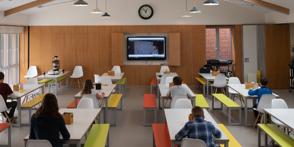 Image of students socially distanced sitting at separate tables in a classroom setting