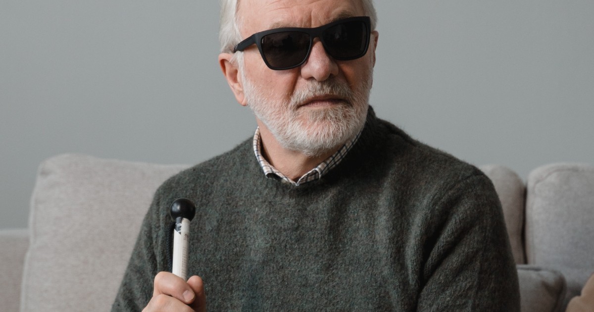 Blind man wearing sunglasses and holding visual impairment stick
