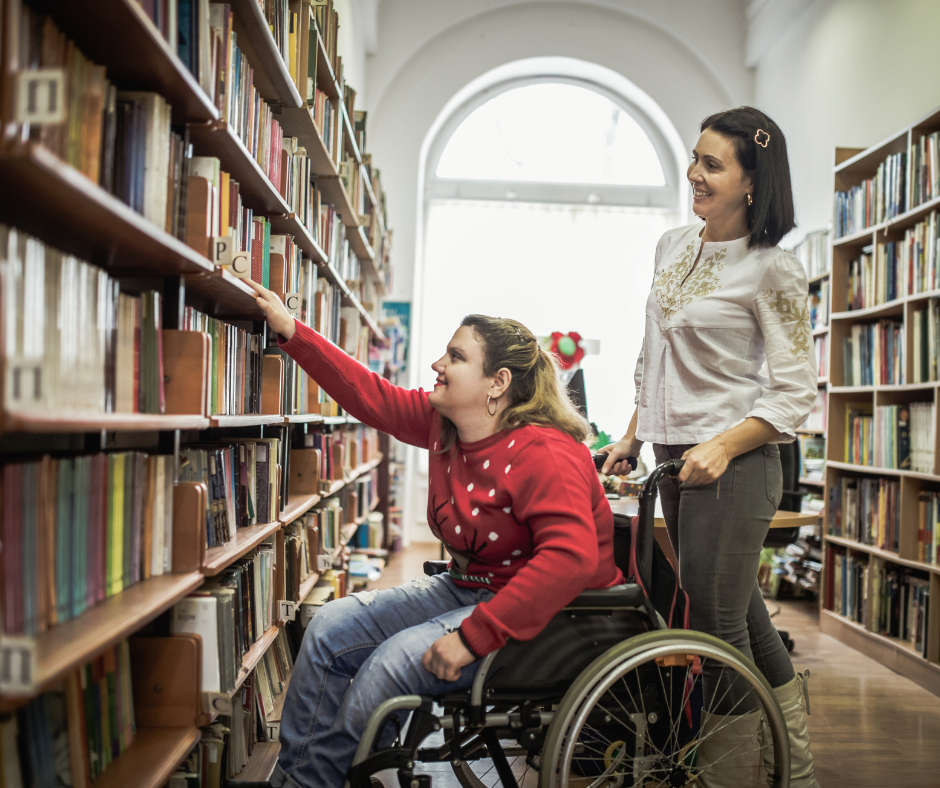 Young woman in a wheelchair picking out a book on a shelf