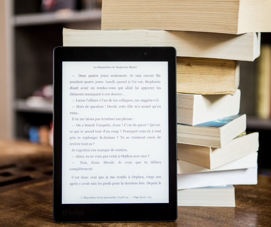 A smart tablet with an ebook loaded onto it, being leant against a tower of books.