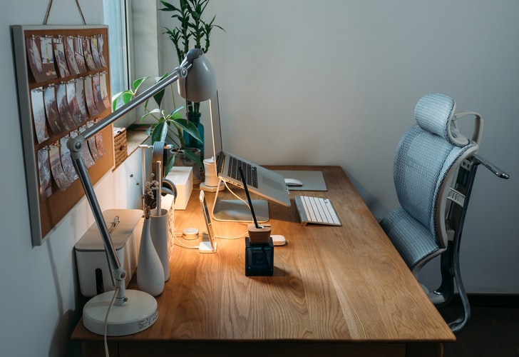 Image of a desk with a desk lamp and a chair and back rest