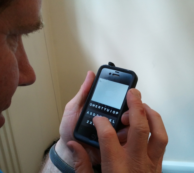 Photo of Rory holding up his iphone, showing the fleksy keyboard in action