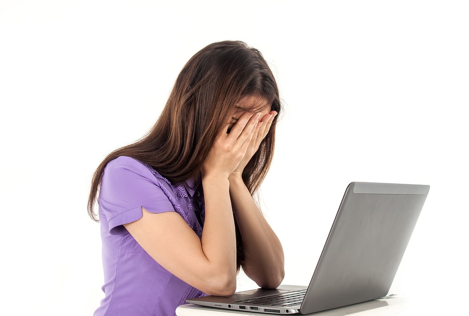 Girl holding her head in her hands in front of her laptop