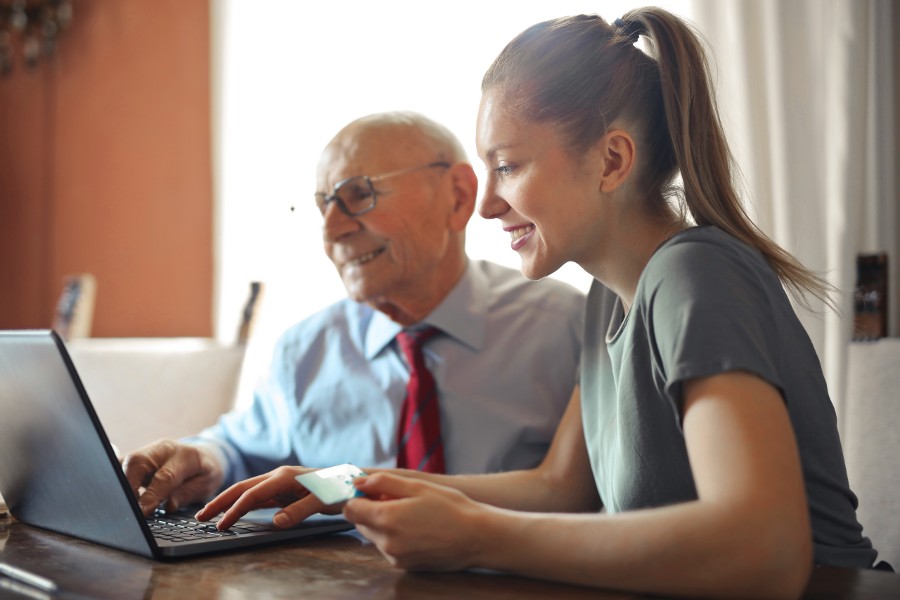Older man and younger woman looking at computer and smiling