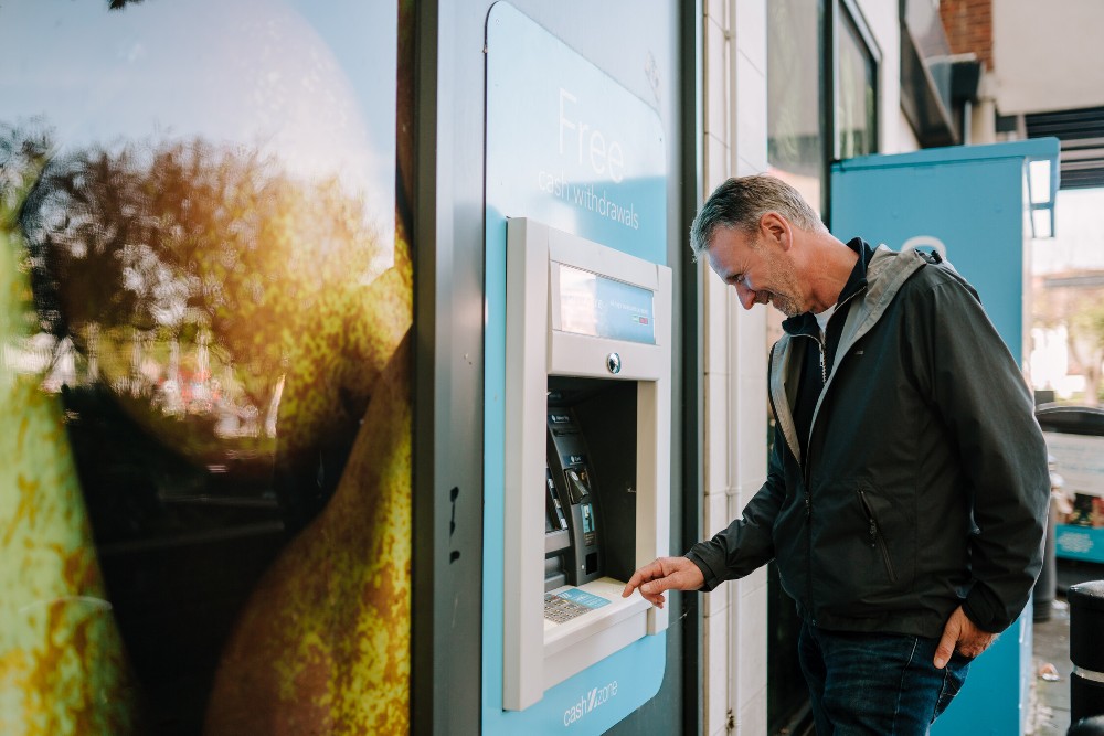 Older man uses ATM and smiles