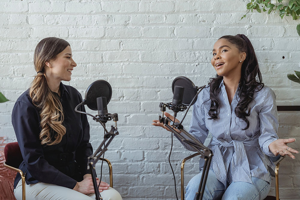 two women in bright studio talking into professional radio microphones