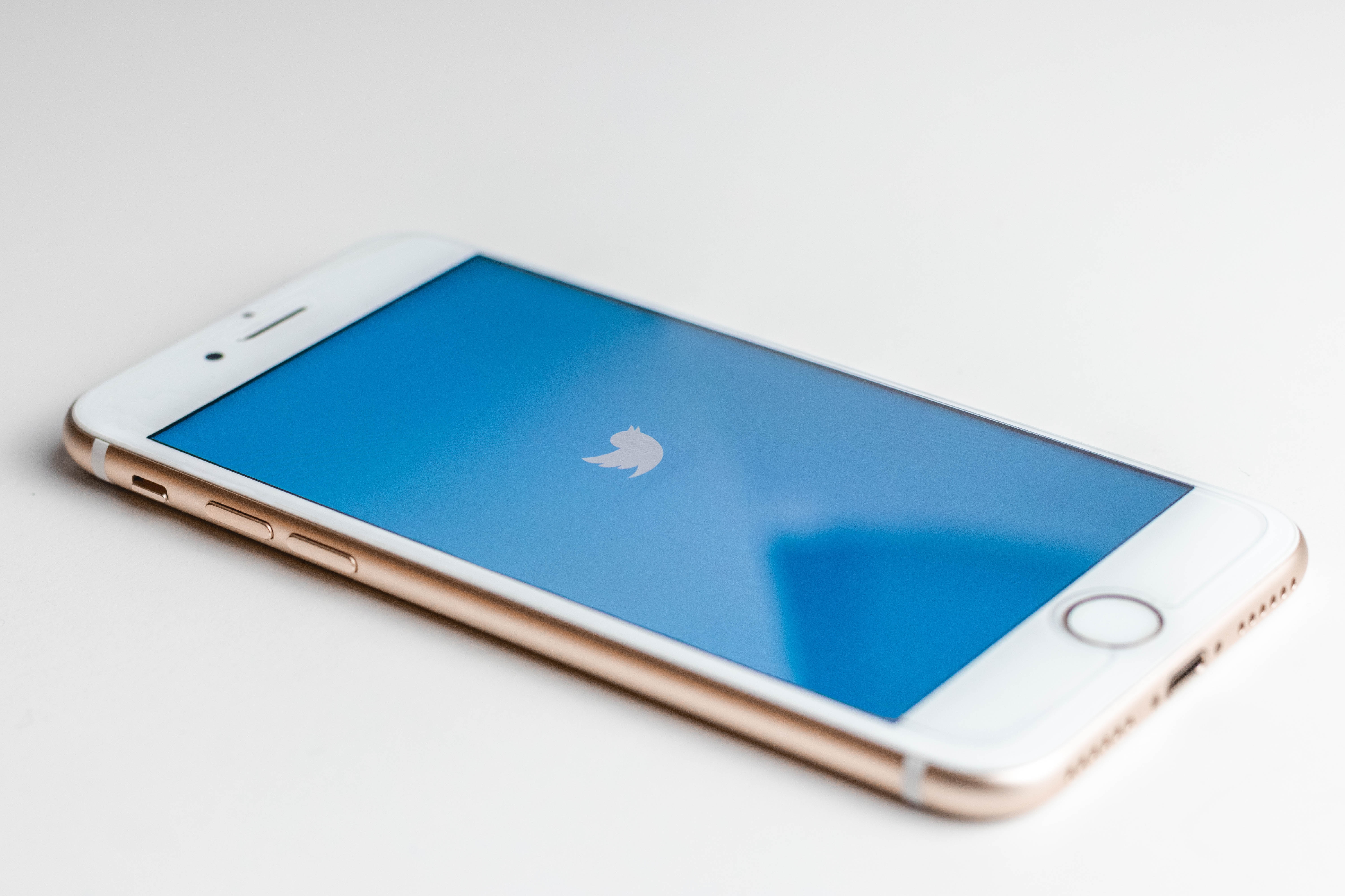 A gold iPhone with a Twitter logo onscreen