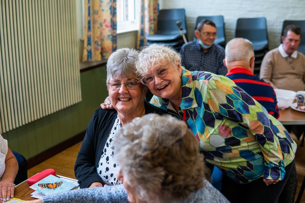 Group of older people in a community hall setting, smiling