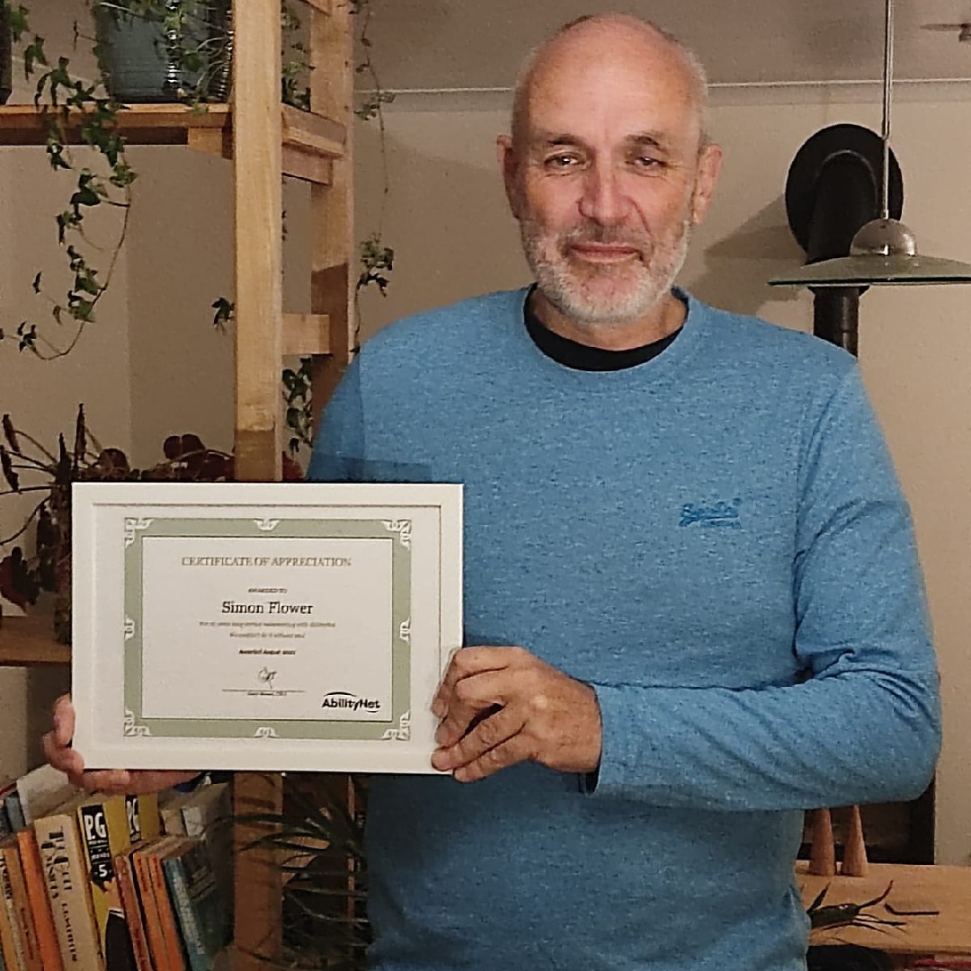 Simon Flower, smiling, holding his certificate