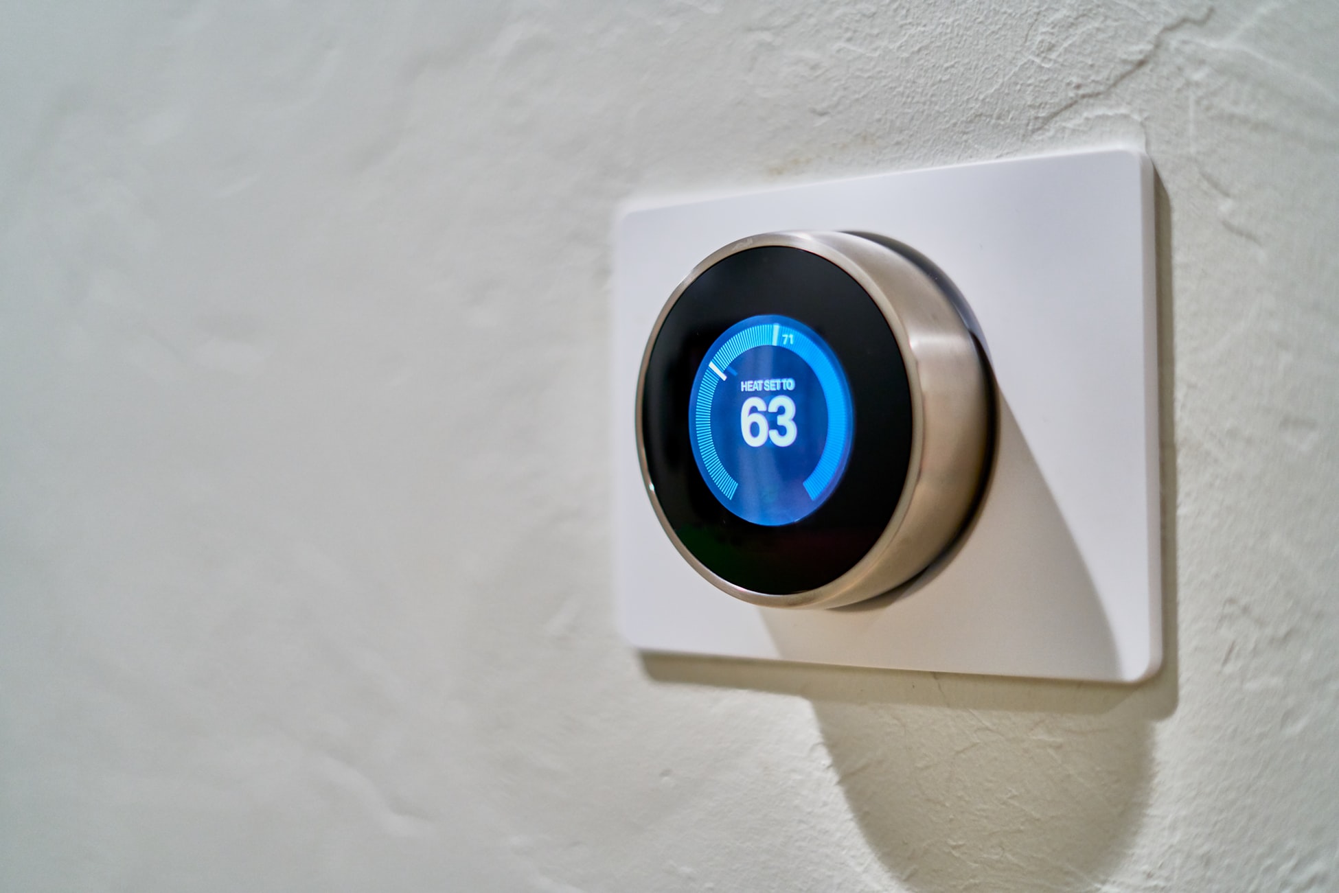 Shows a thermostat on a wall with a blue, digital display