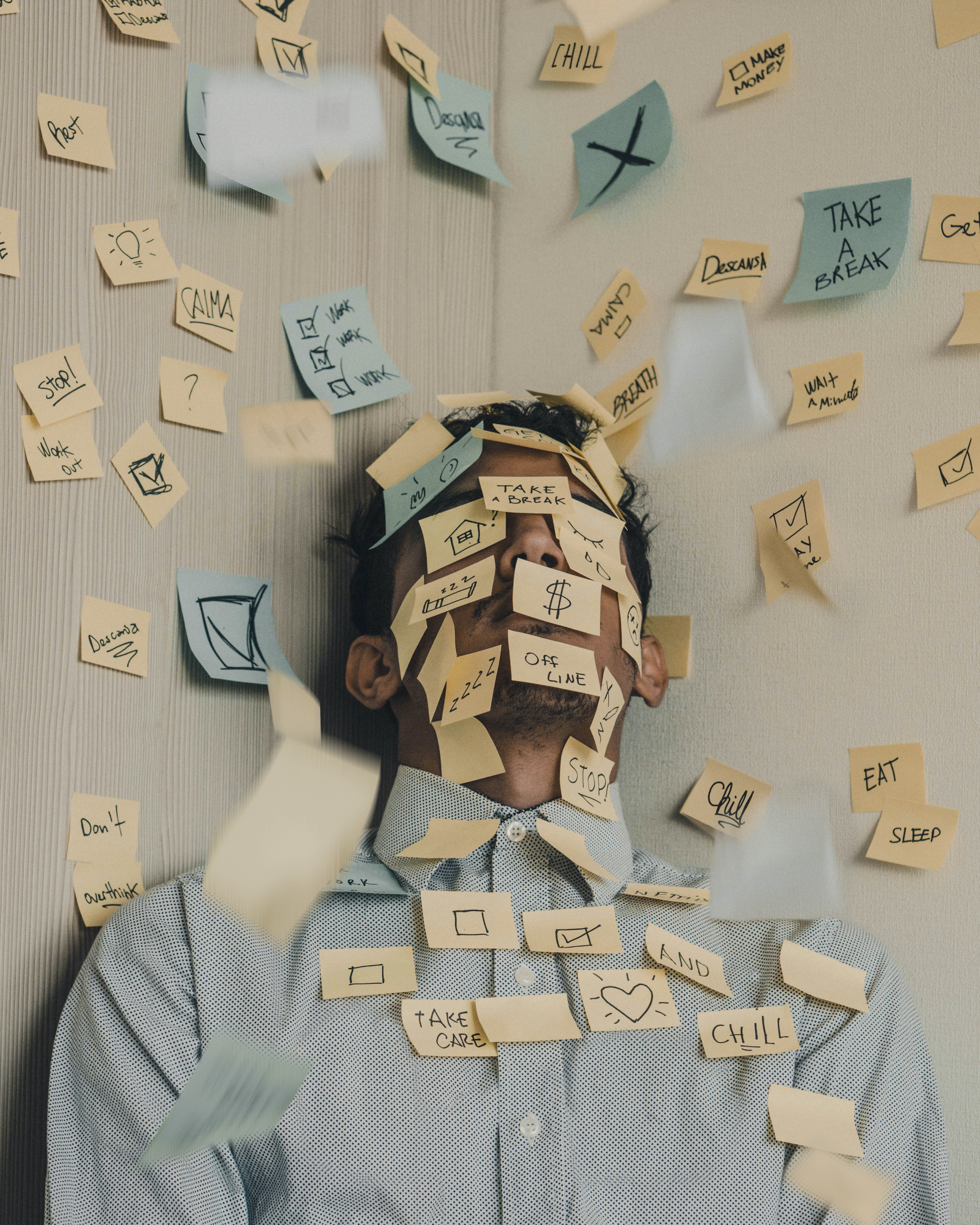 Image shows a man covered with a plethora of post-it notes all scribbled on.