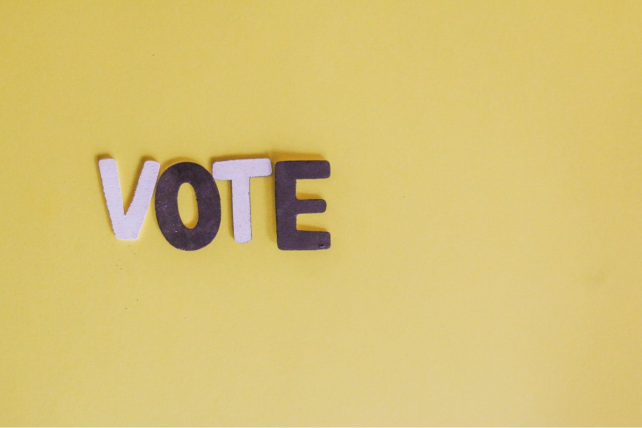 'Vote' word spelled out in cut out letters on yellow background
