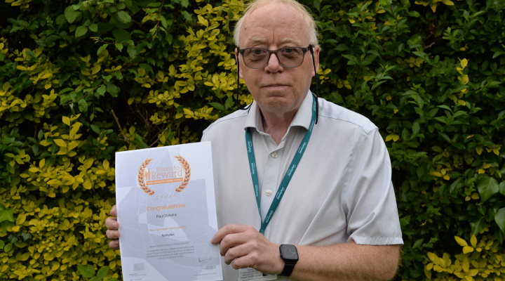 Paul Dykstra holding his certificate standing in garden