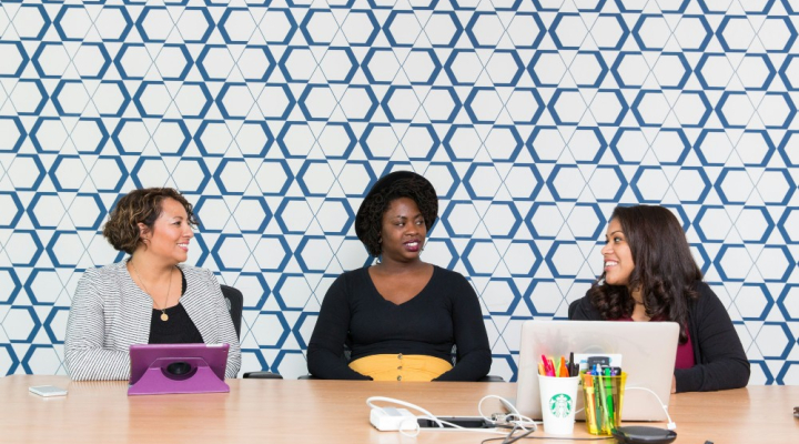 Three women sitting in smart environment with patterned wall in background