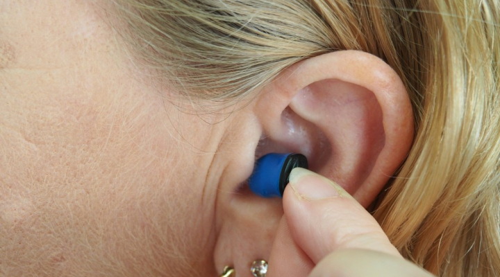 Woman pointing at earplug in her ear 